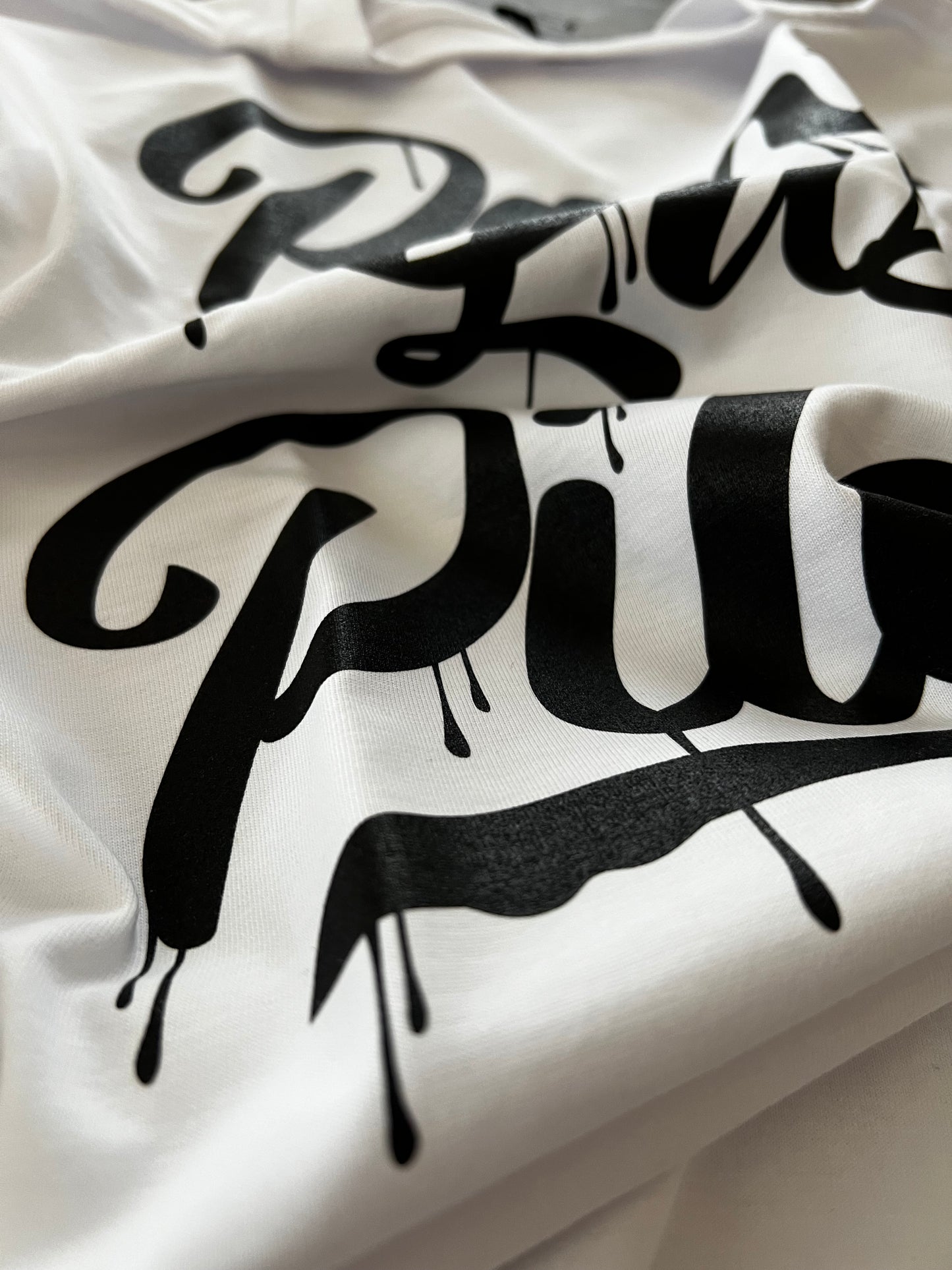 White Pilas Clothing Co. PLP Drip t-shirt featuring black graffiti-style 'Ponte Las Pilas' text with paint drip effect - Latino motivational apparel