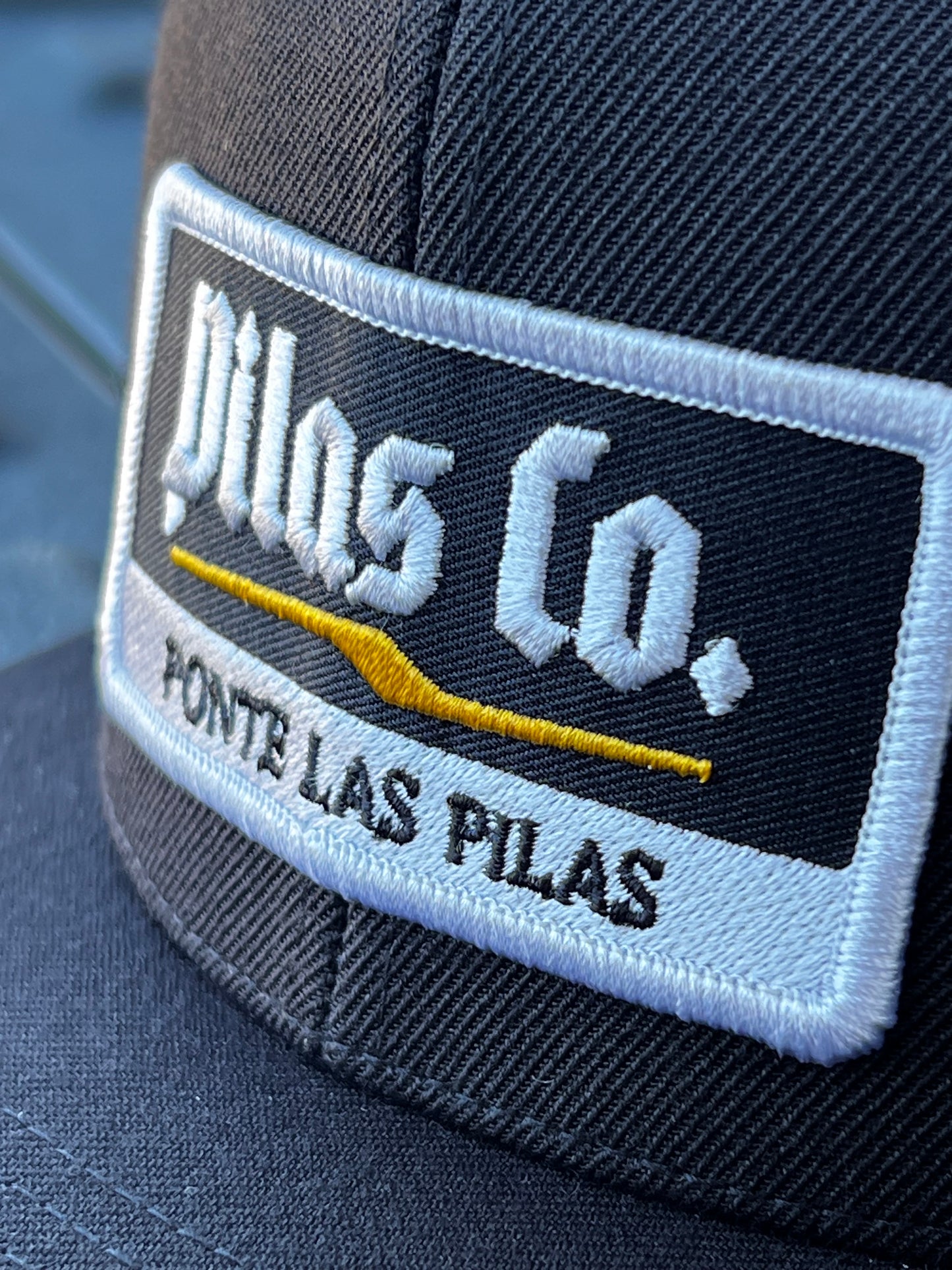 Pilas Co Ponte Las Pilas embroidered badge close-up - premium Latino workwear trucker hat patch detail