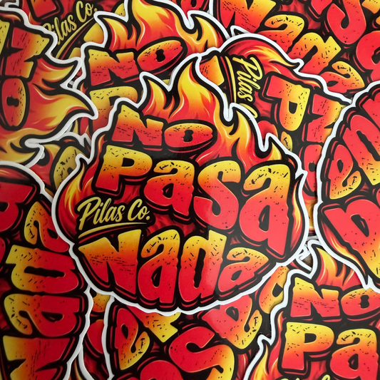 A close-up of a repeating graphic sticker or print design featuring the words 'No Pasa Nada' in bold red and yellow lettering with flame shapes and 'Pilas Co.' in smaller script.